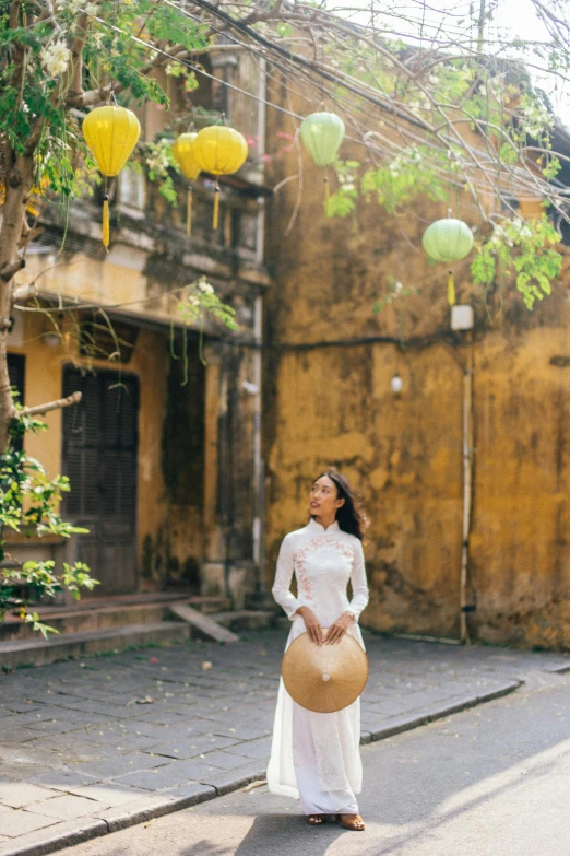 a woman standing in the middle of a street next to yellow lanterns