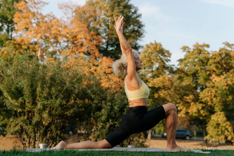 a woman doing yoga on a blanket in the park