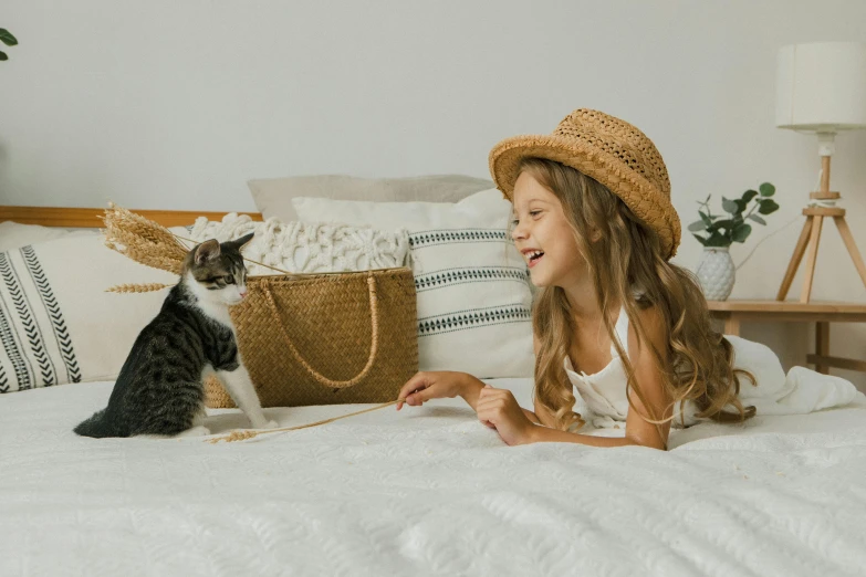 a little girl laying on a bed next to a cat