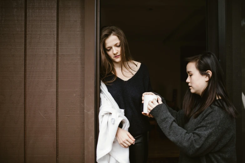 two s standing by a door with their hands together