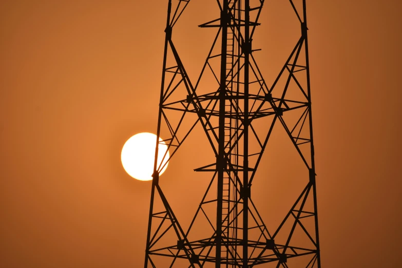 the sun is behind the high voltage tower