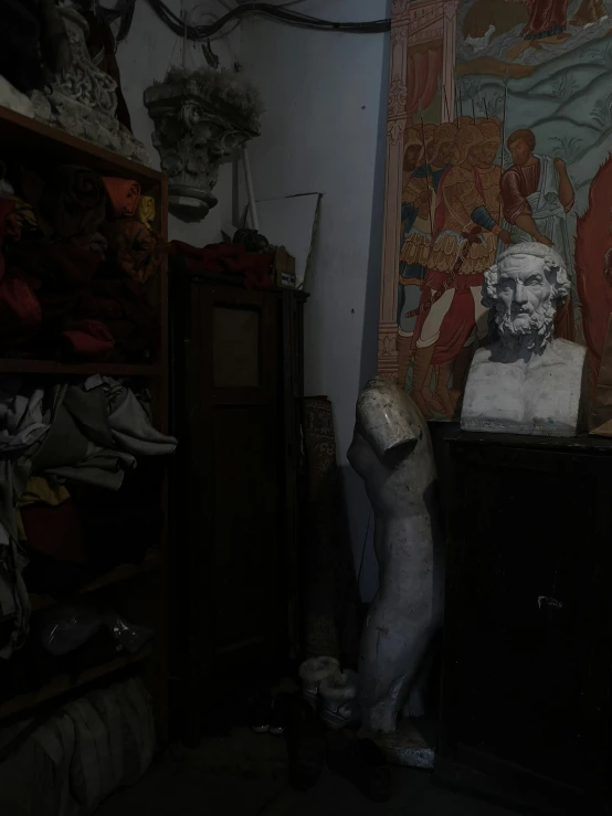 an older looking statue stands alone in front of some other antique furniture