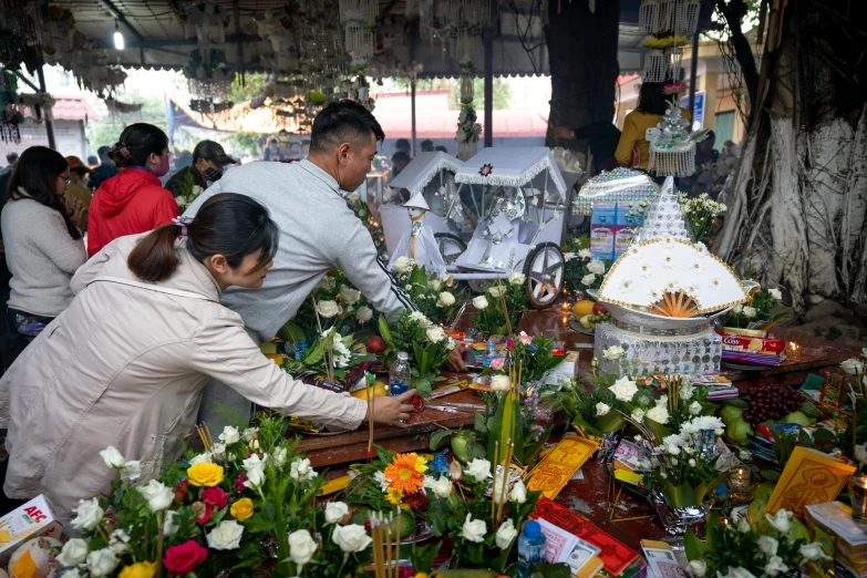 several people are standing around a table with flowers on it