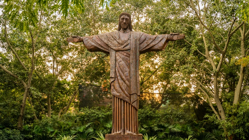 a statue of jesus surrounded by trees and bushes