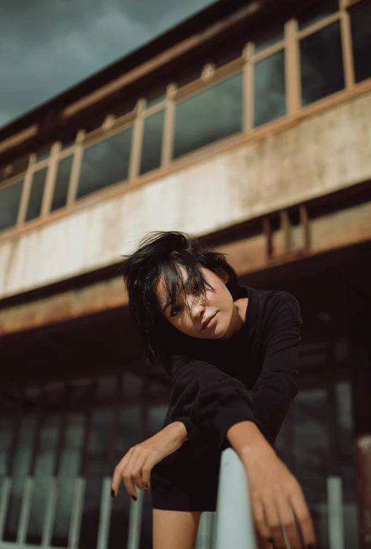 a woman in black dress leaning on a railing