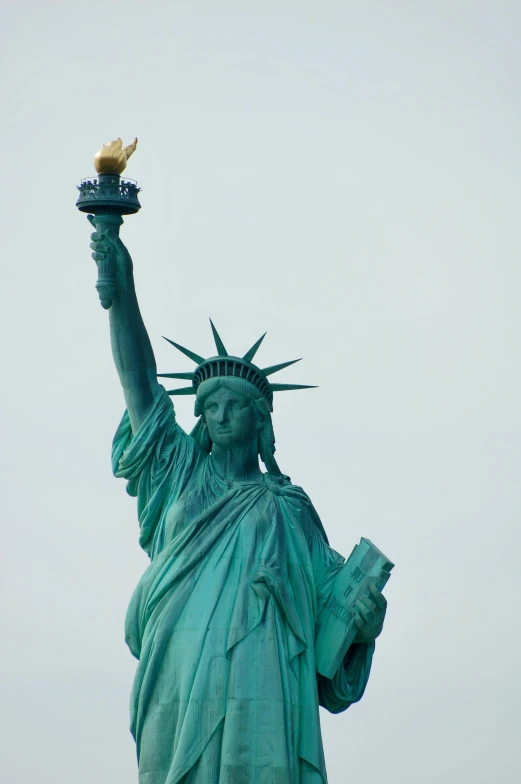 the statue of liberty stands tall, holding an umbrella in the air