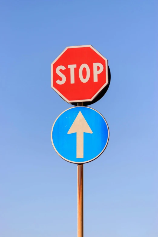 two stop signs on top of each other with the right sign pointing left