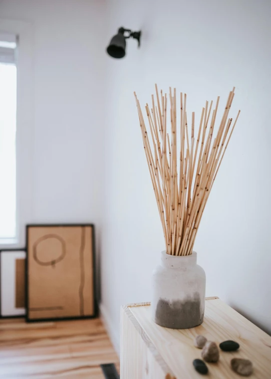 a vase filled with wooden sticks sitting on top of a table