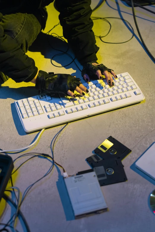 a persons hand typing on the keyboard surrounded by electrical wires