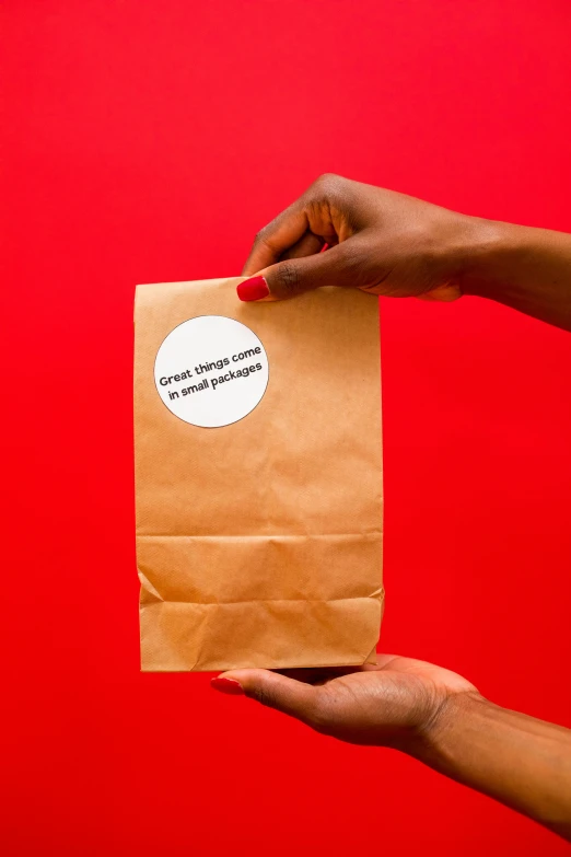 a hand holds a brown envelope with a round sticker in it