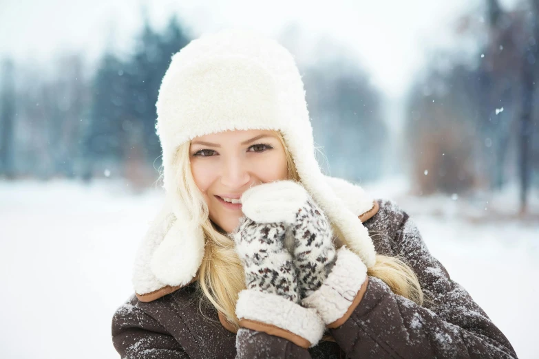 a woman is holding her mittens on in the snow