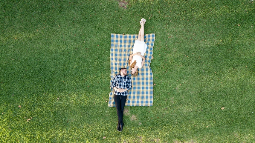 a man and his dog laying on a blanket in the grass