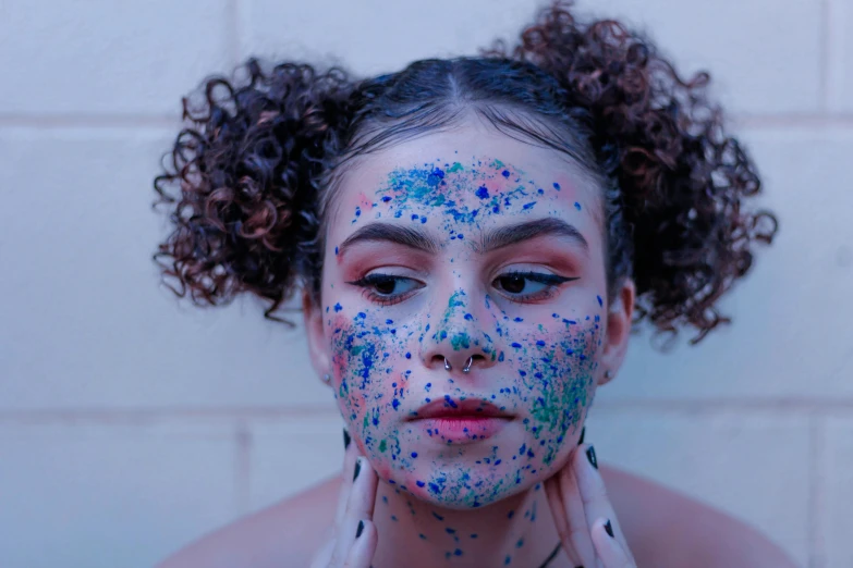 a woman with her face painted with blue and pink colors