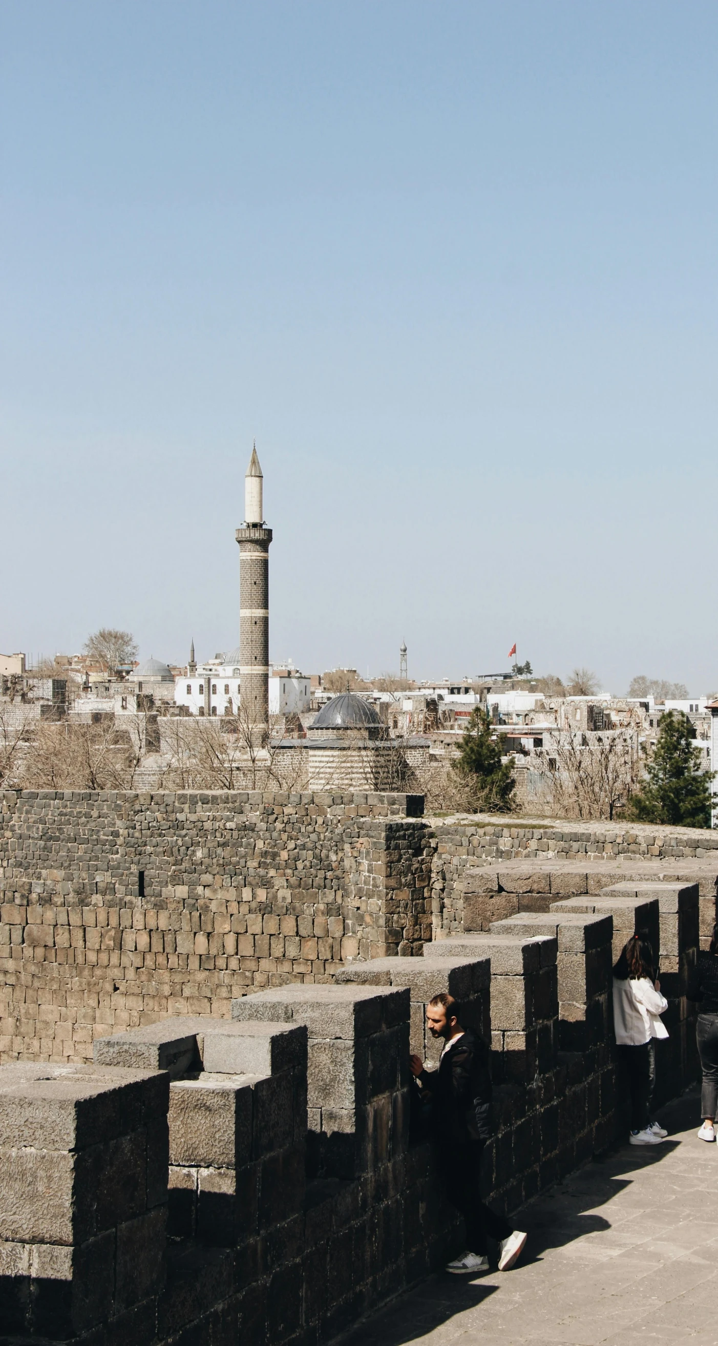 people walking down a very old bridge overlooking an ancient city