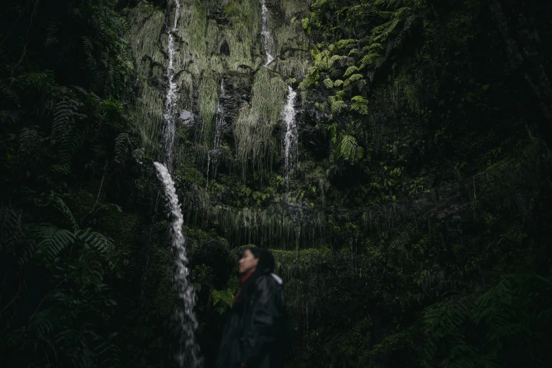 a man is staring up at a tall waterfall