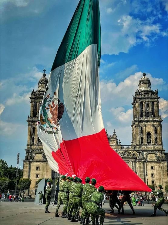 a group of men with a huge flag next to an audience