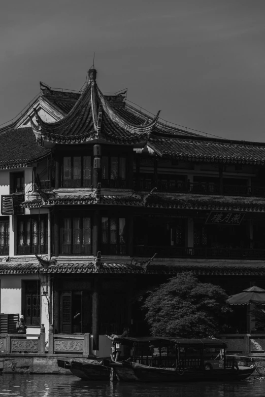 an asian building with two boats passing it by