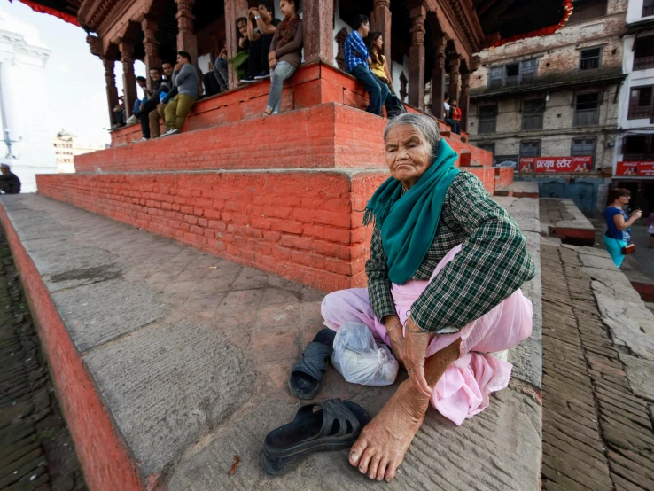 a smiling elderly lady sitting down in front of a building