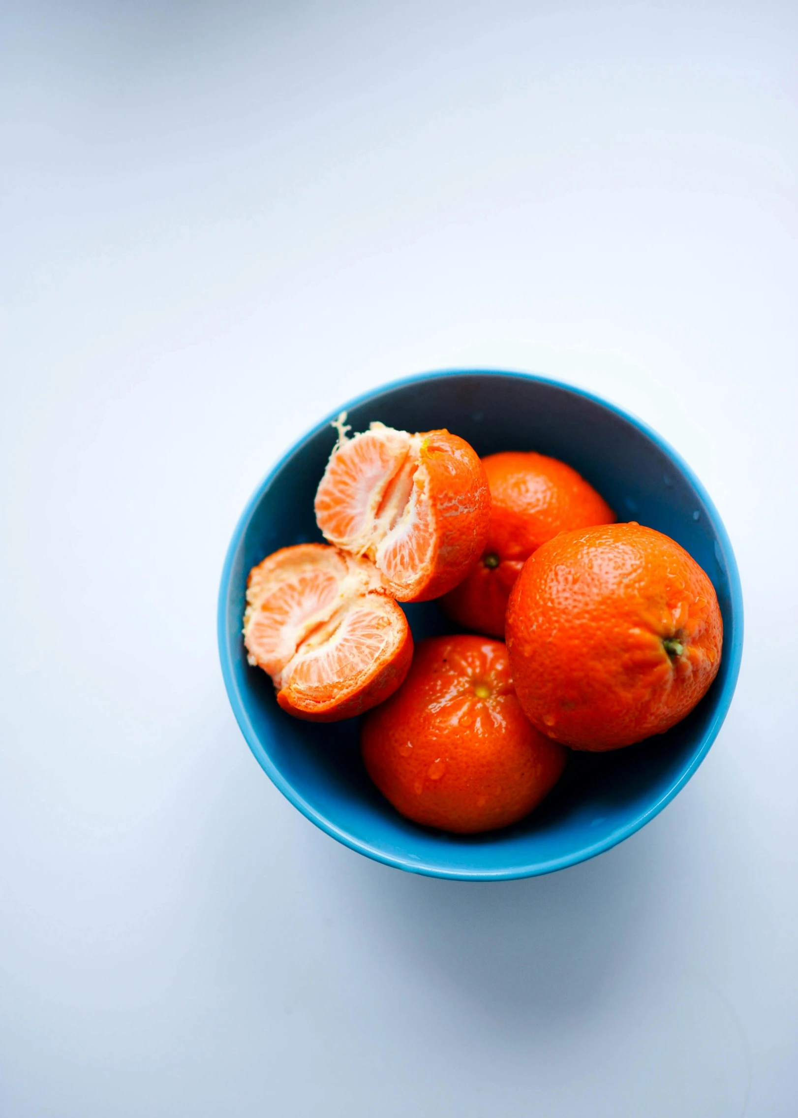 there is a blue bowl full of tangerines