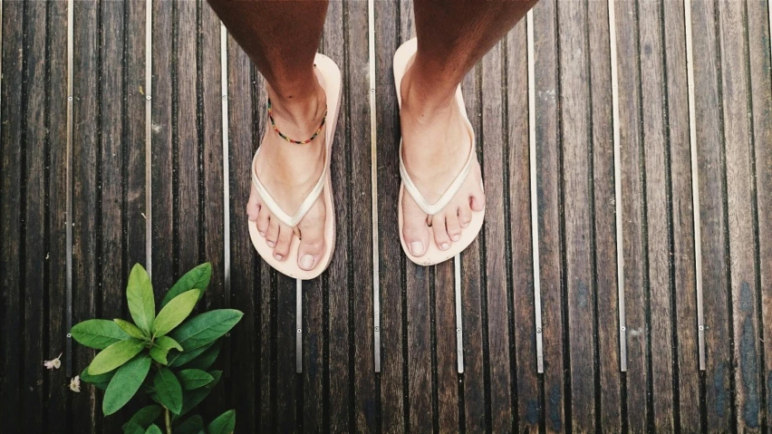 the bare legs of a person standing over a wooden surface