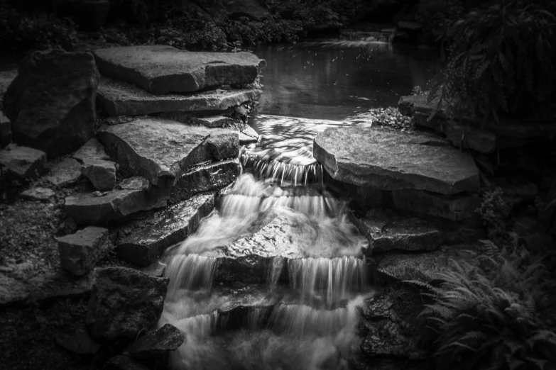 a small waterfall flowing down a dark green forest