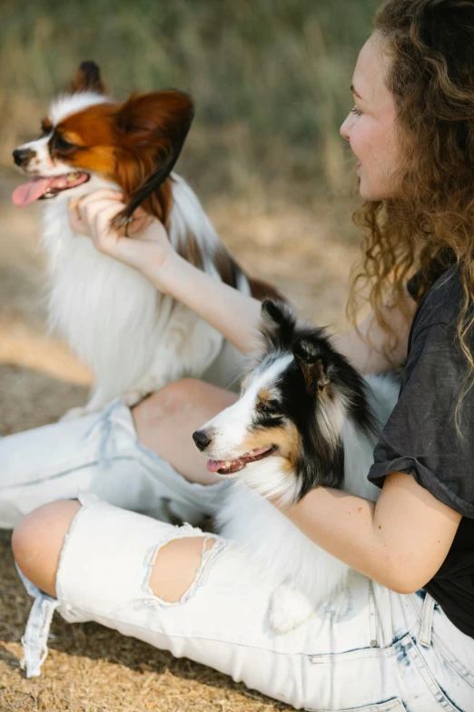 a girl sitting on the ground with three dogs