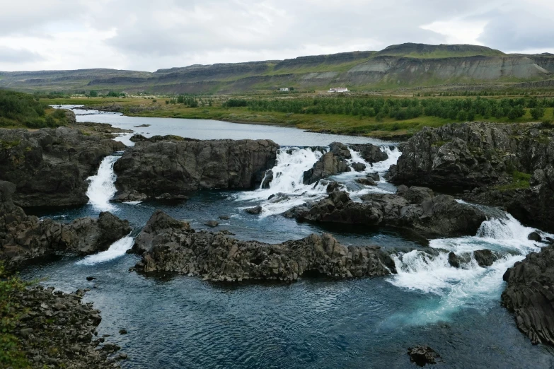 a small waterfall on the edge of a lake in the mountains