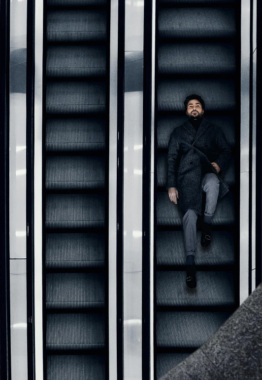 a man sitting on the edge of a silver metal elevator