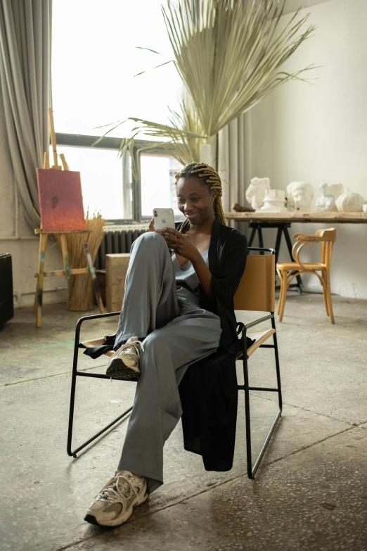 a woman sitting in a chair while looking at her phone