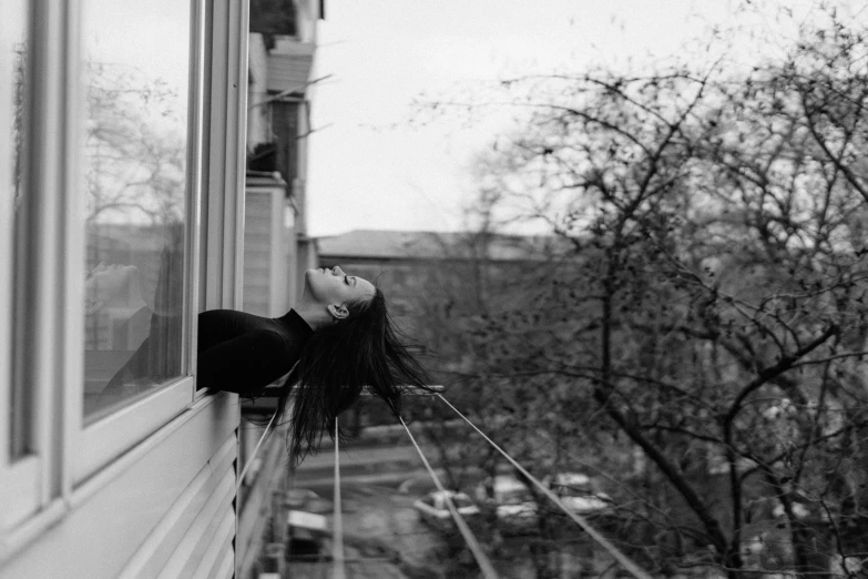 woman leaning out window while standing outside looking outside