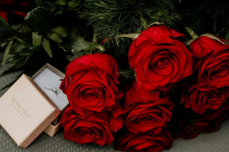 a ring in a box with several red roses