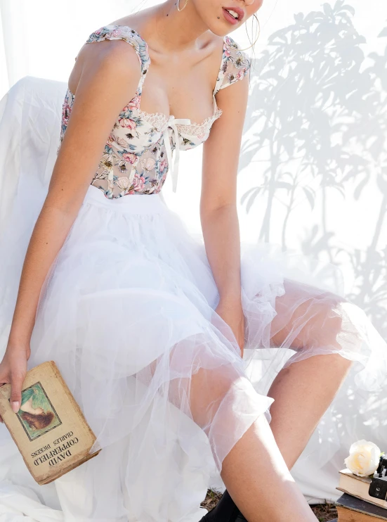 a woman in white dress sitting on a book