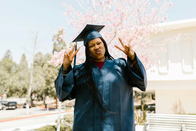 a young black student dressed in a graduation gown standing outside