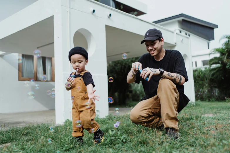 man with child blowing bubbles in yard