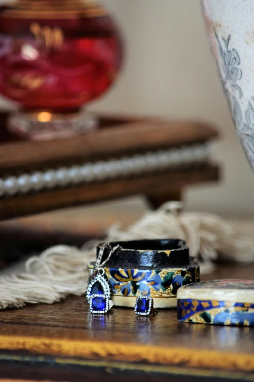 small ring and celet sitting on a table near a vase