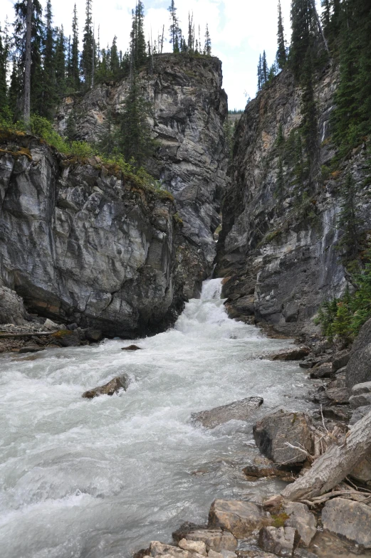 a river flowing under mountains near some rocks