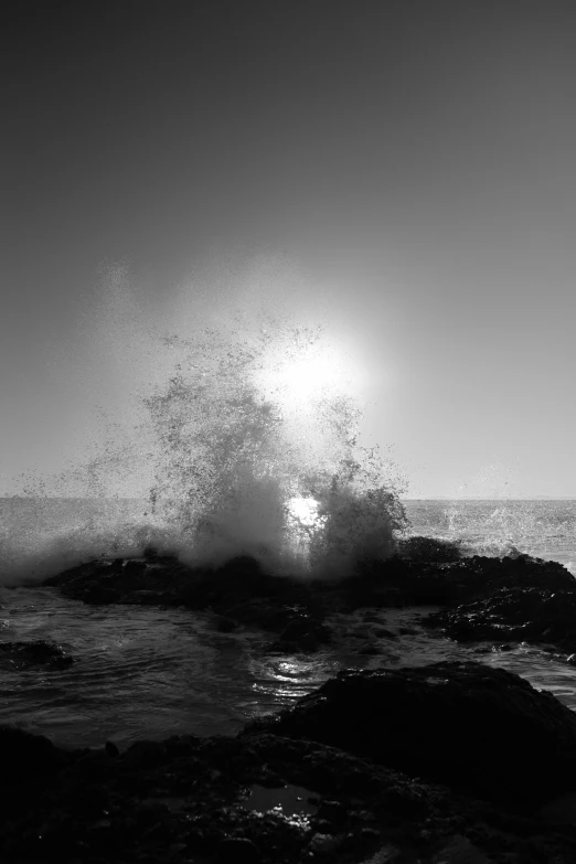 sun reflecting off ocean with rocks on shore