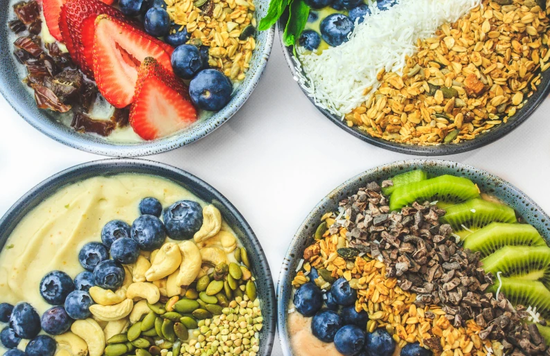 four bowls of healthy fruit and granola meal