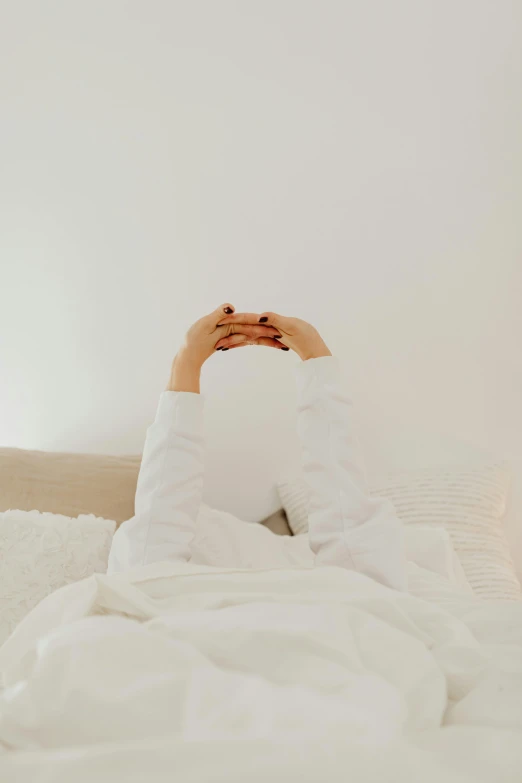 a person laying in bed holding his legs up