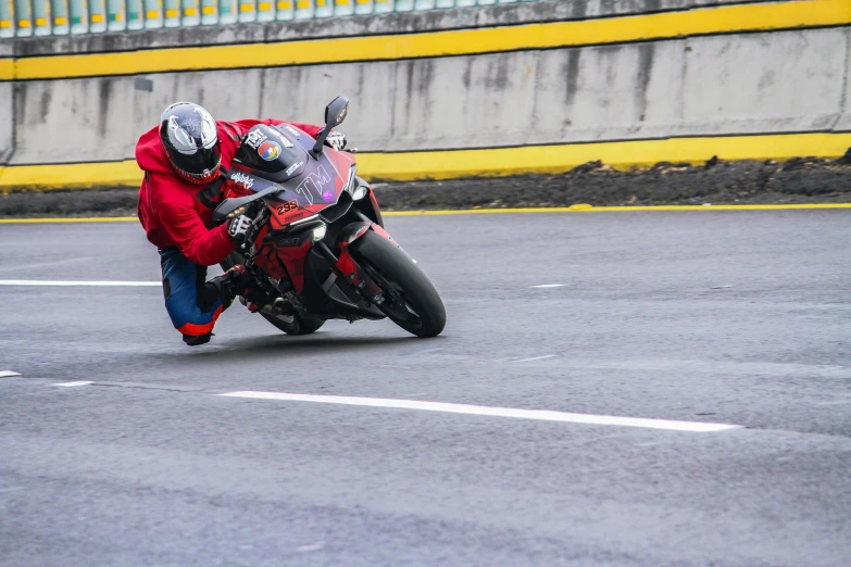 a person riding on the back of a red motorcycle down a road