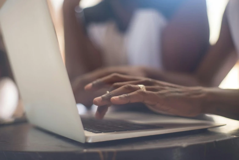 the woman's hands are on top of the laptop