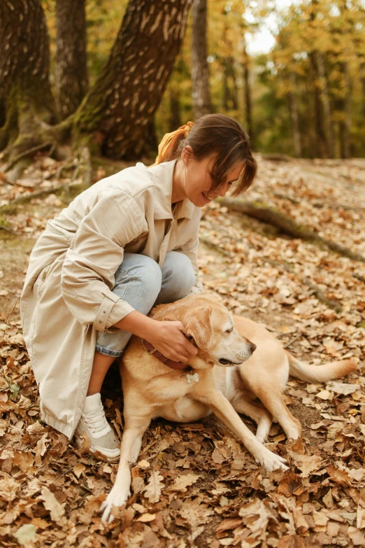 a woman and her dog are playing in the leaves