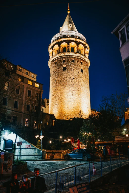 a clock tower at night with people walking around