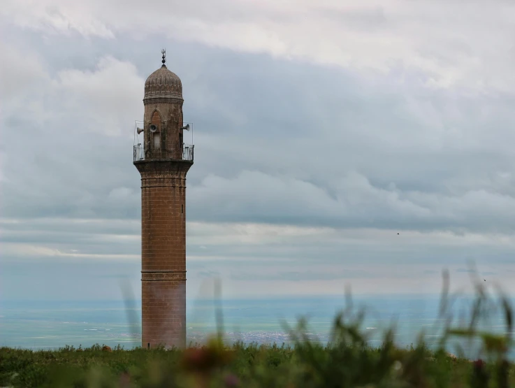 an old tower with a flag on top sitting in the grass