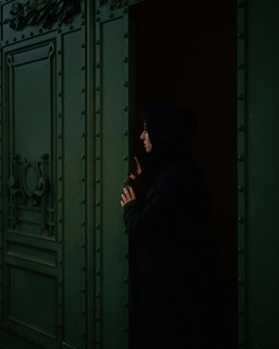 a person in a hooded sweatshirt in front of an open door