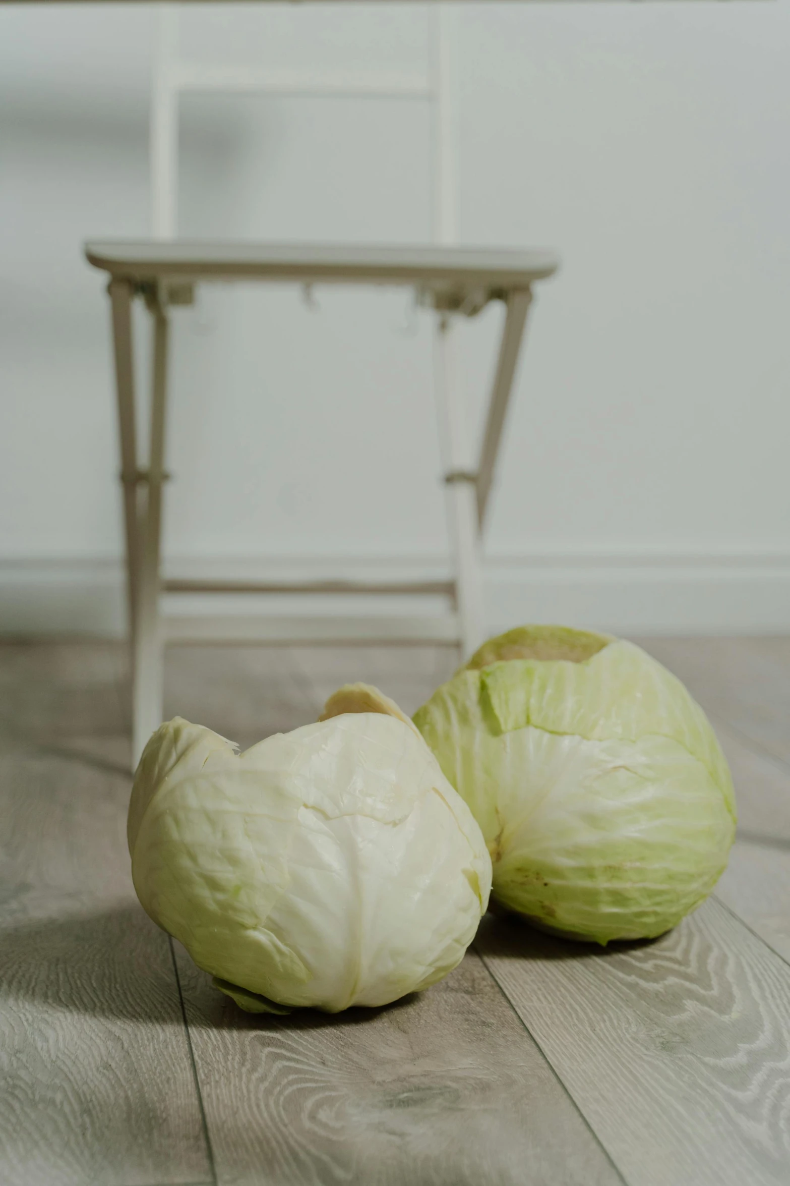 some head cabbage sitting on the floor next to a table