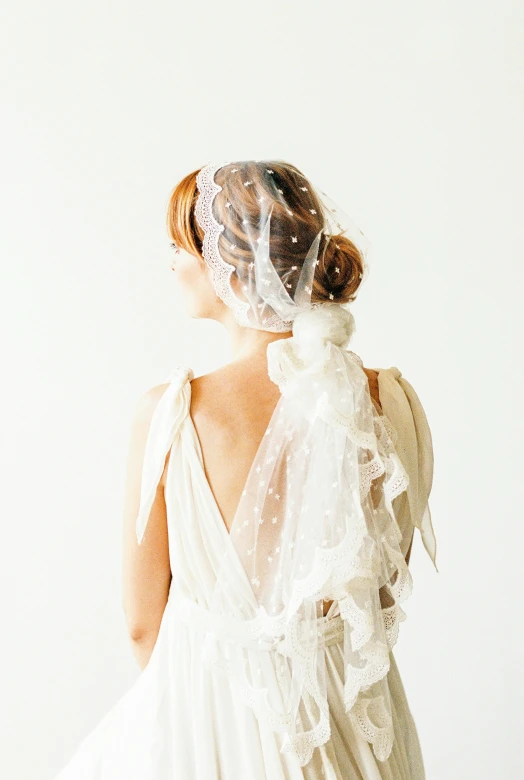 a bride with a veil on her head is standing in a room