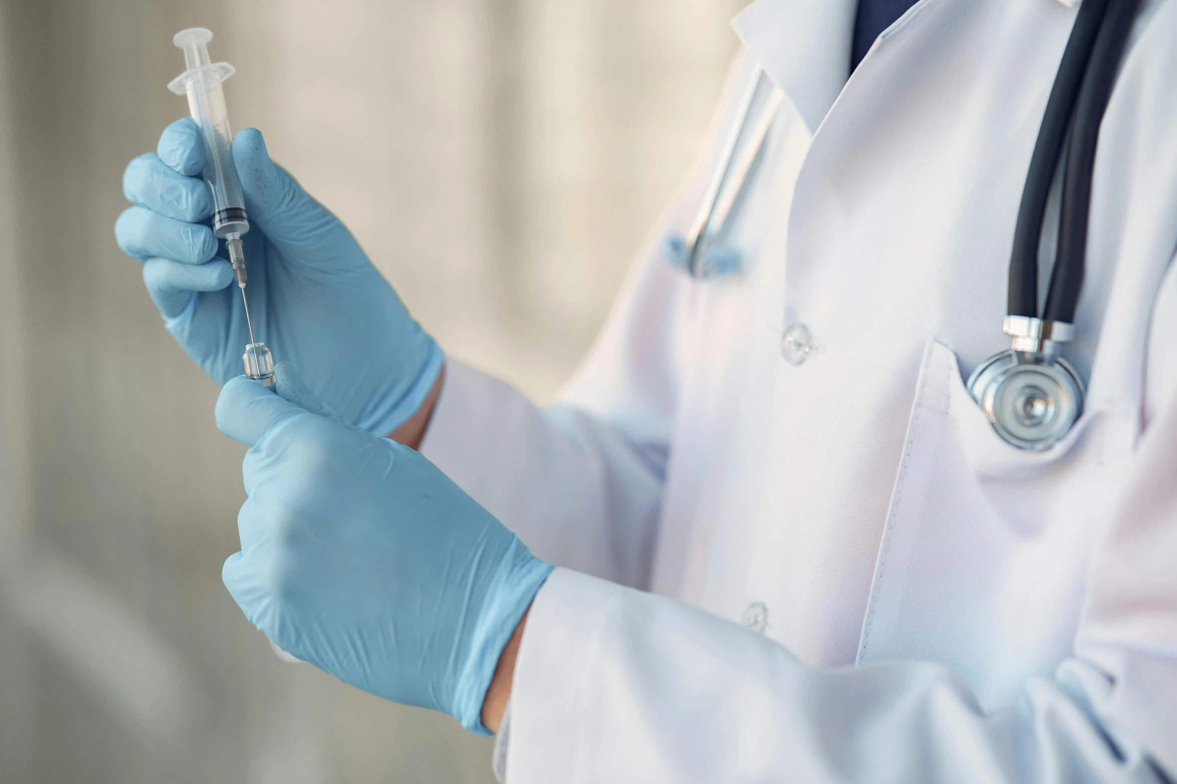 an older doctor's gloved hands holding a syula