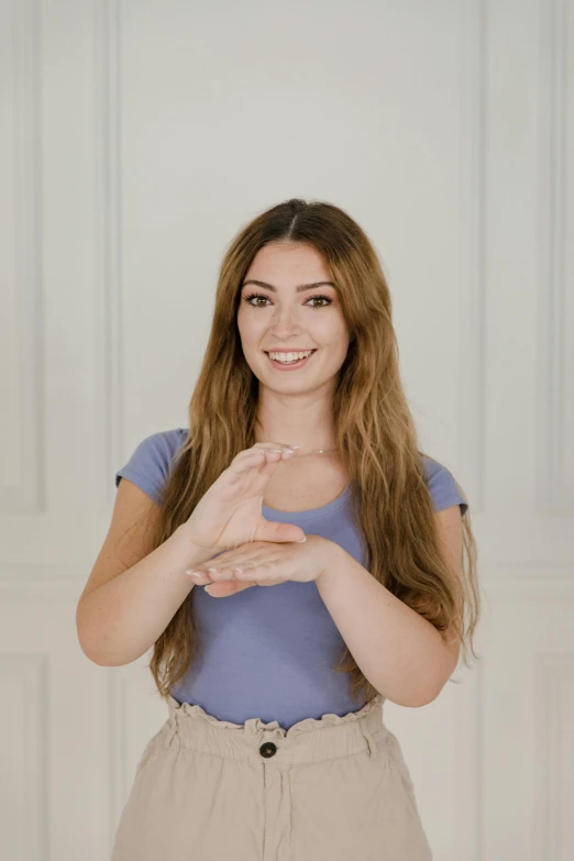 a woman smiling while standing with her hands together