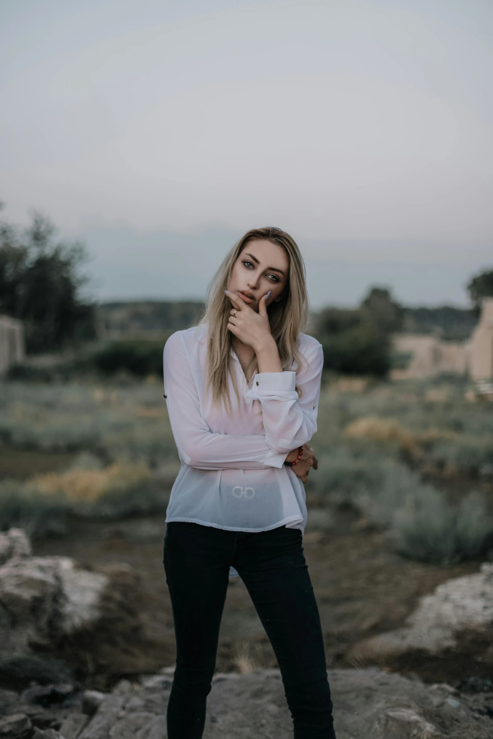 a beautiful young blonde woman poses in a deserted place